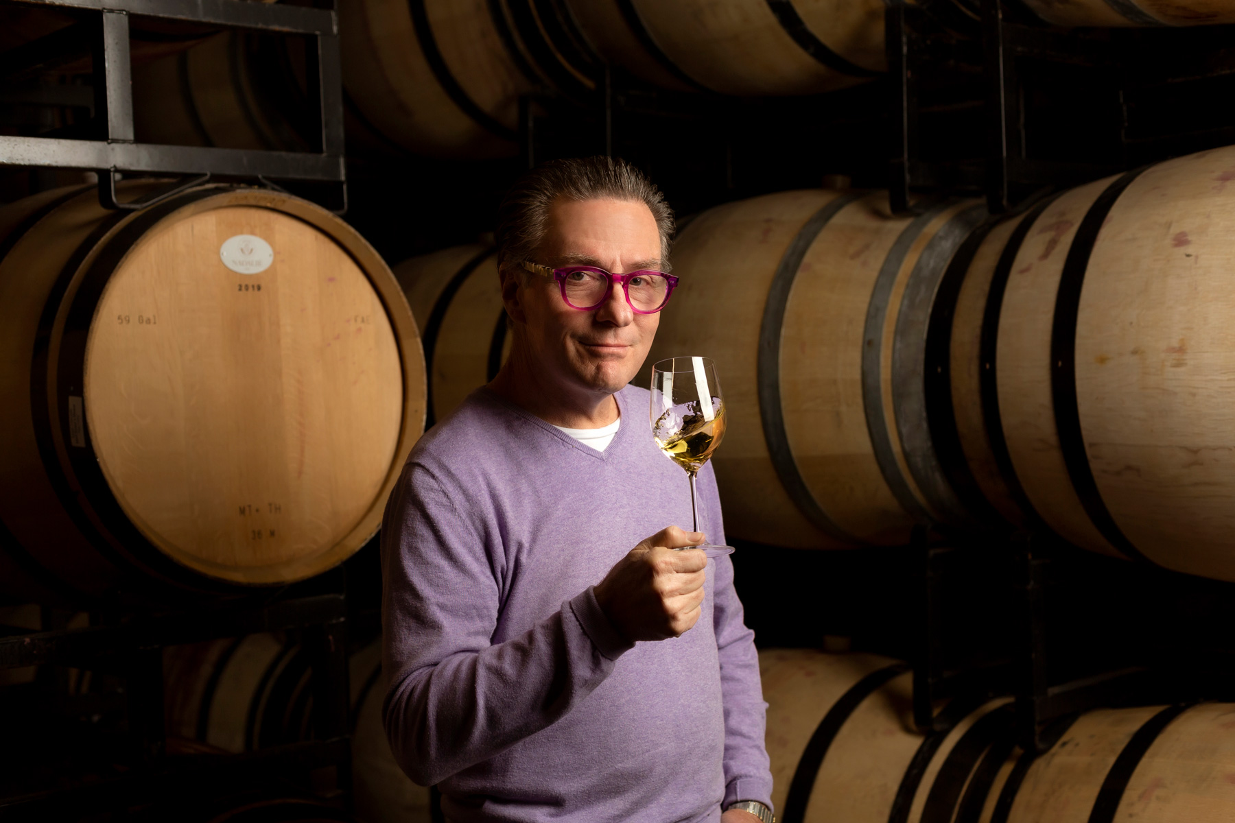 Vance Rose, Jonive Winemaker posing in front of a barrel at the winery.